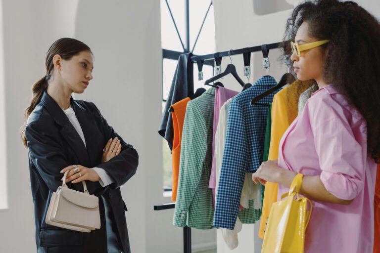 Two women browsing colorful clothing racks in a modern boutique.